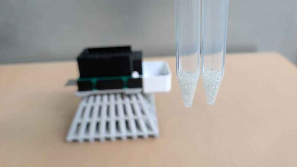 Two 15 mL conical tubes each holding 1.5 grams of glass beads after one dispensing stroke